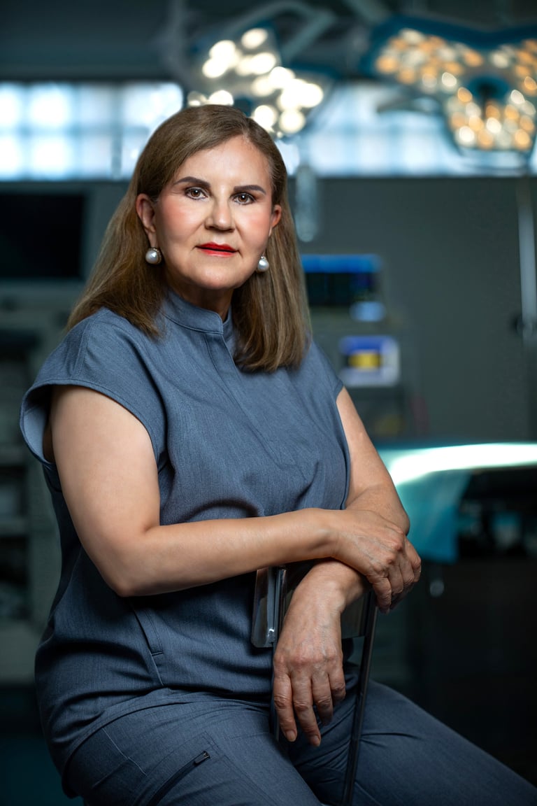 Woman in blue denim shirt sitting with arms crossed in modern control room with illuminated screens
